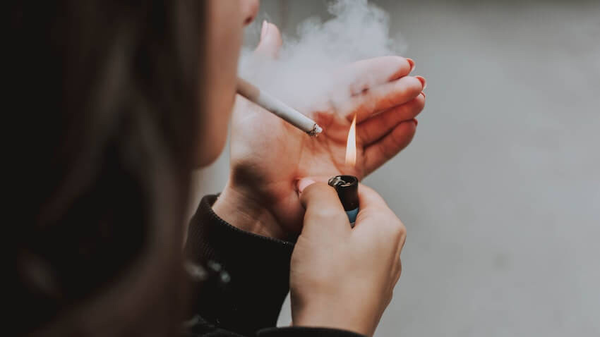 femeie care isi aprinde o tigara