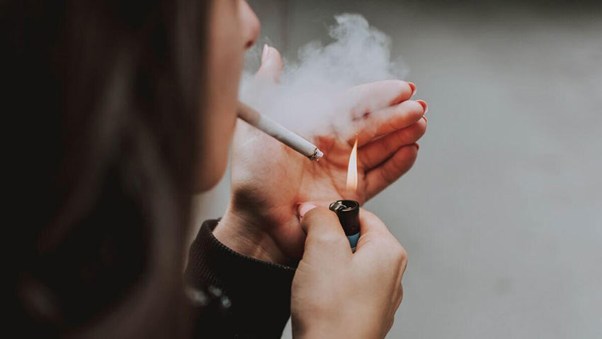 femeie care isi aprinde tigara cu o bricheta cu gaz