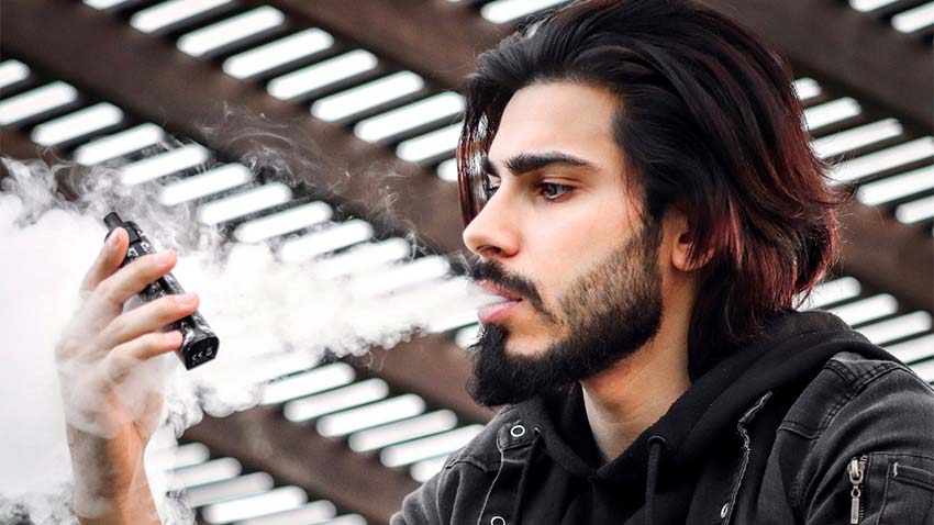 barbat care fumeaza dintr-o tigara electronica