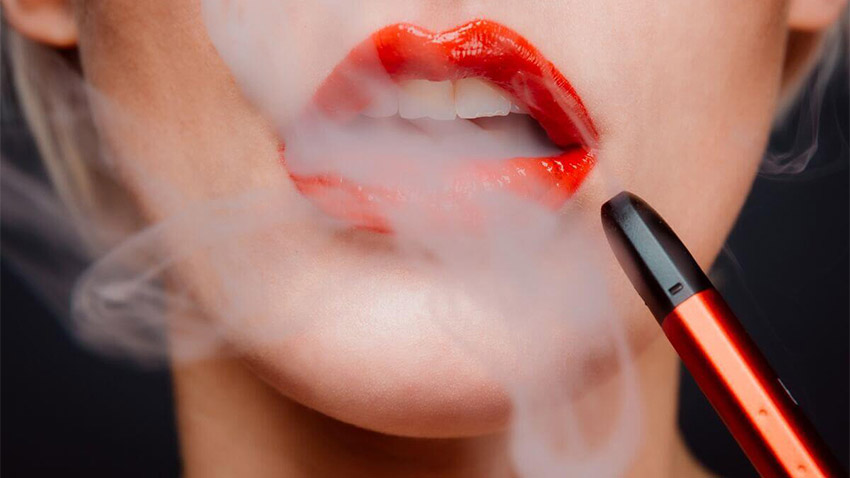 femeie care fumeaza dintr-o tigara electronica