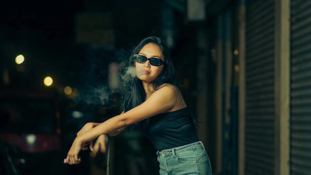 femeie cu ochelari de soare care fumeaza mini narghilea