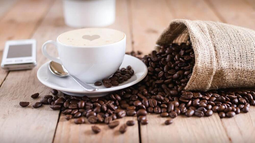cana de cafea cu boabe de cafea langa