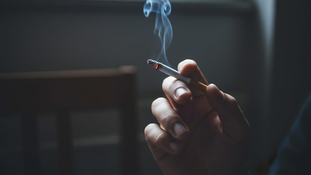 Persoana care fumeaza o tigara